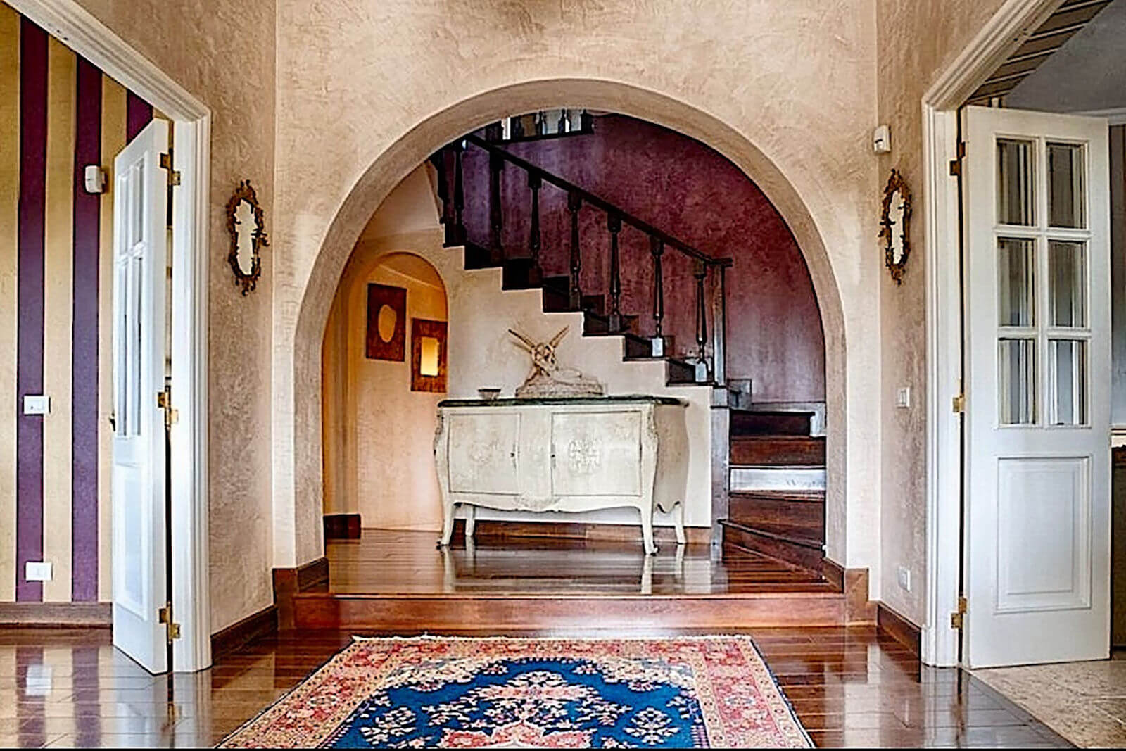 Elegant entrance hall at Villa InCanto with curved staircase and antique furnishings